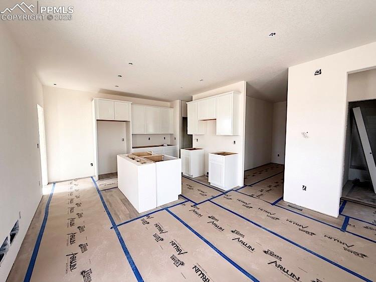 Image 6 of 33: Kitchen with quartz countertops, pantry, island providing seating, and stai