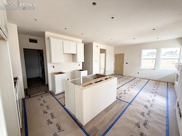 Image 7 of 33: Kitchen with quartz countertops, pantry, island providing seating, and stai