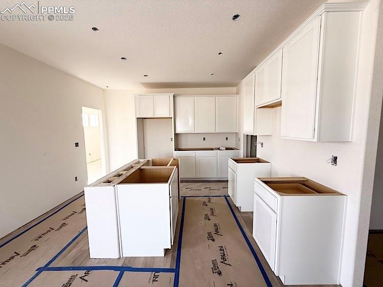 Image 8 of 33: Kitchen with quartz countertops, pantry, island providing seating, and stai