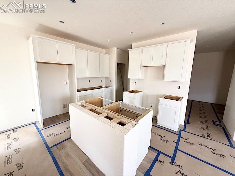 Image 9 of 33: Kitchen with quartz countertops, pantry, island providing seating, and stai