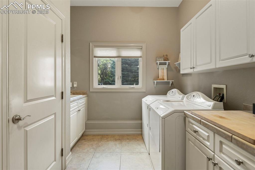 Image 13 of 39: Washroom with cabinet space, light tile patterned floors, and independent w