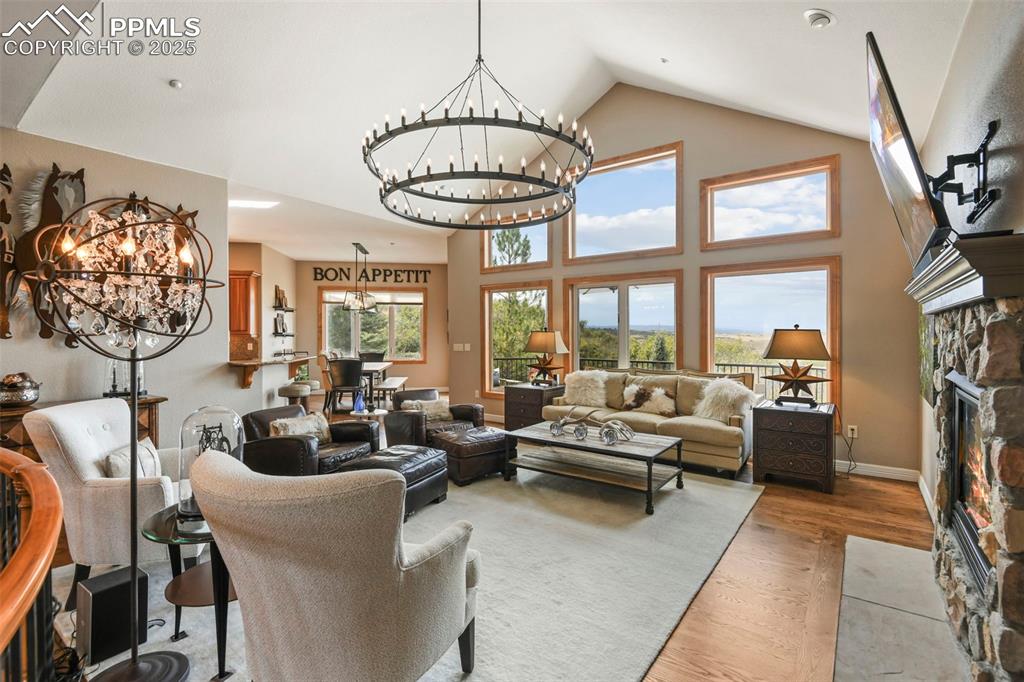 Image 3 of 39: Living area featuring a chandelier, a stone fireplace, wood finished floors