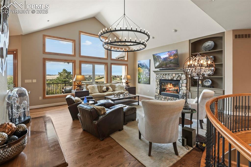 Image 4 of 39: Living area featuring a chandelier, a fireplace, built in shelves, wood fin