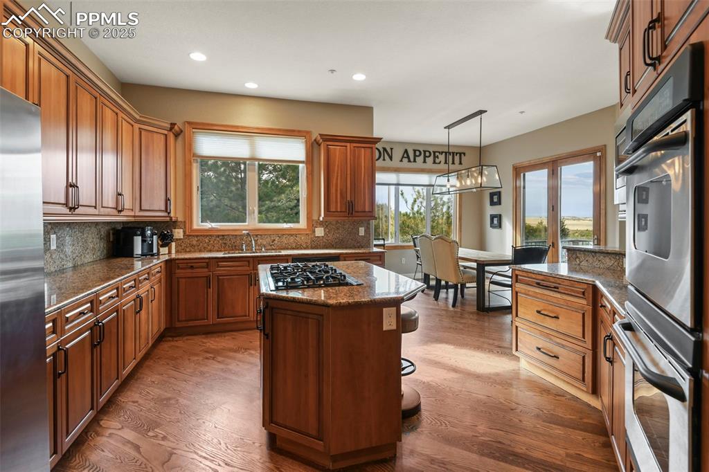 Image 8 of 39: Kitchen featuring appliances with stainless steel finishes, brown cabinetry
