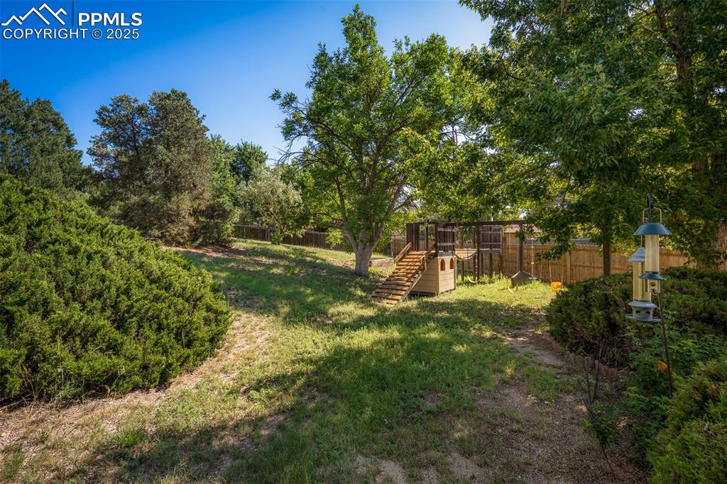 Image 17 of 49: Fenced backyard with a playground
