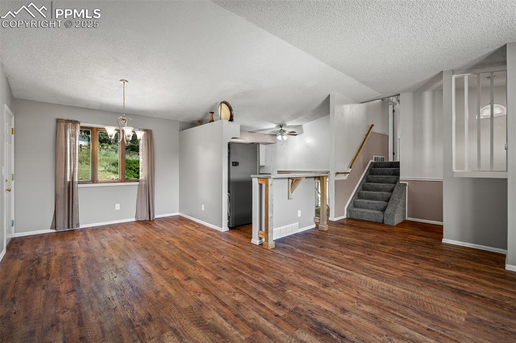 Image 21 of 49: Unfurnished living room featuring stairs, dark wood finished floors, a chan