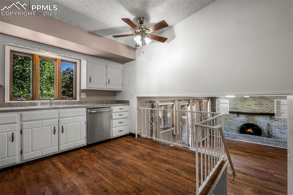 Image 26 of 49: Kitchen featuring white cabinetry, stainless steel dishwasher, light counte