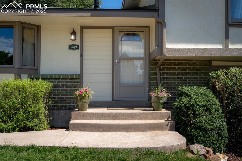 Image 47 of 49: View of exterior entry with brick siding and stucco siding