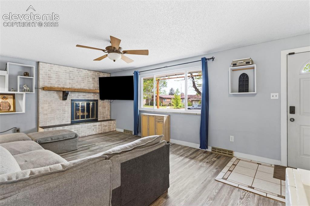 Image 4 of 37: Spacious living area featuring a wood-finish plank floor, ceiling fan with