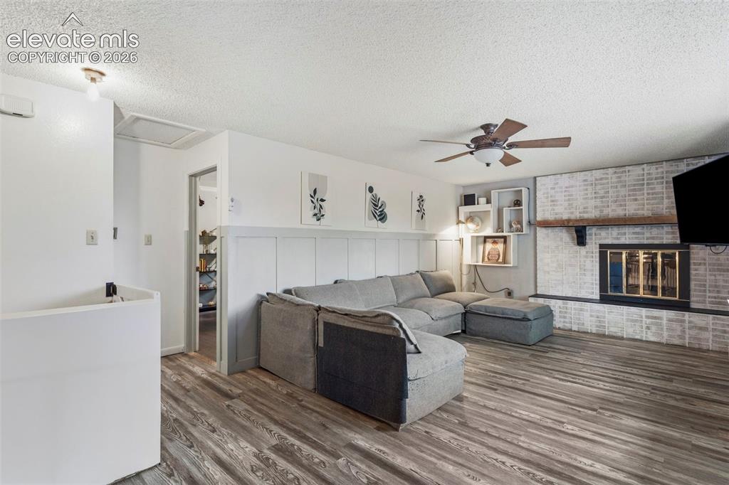 Image 5 of 37: Living area featuring wood-finish flooring, a brick-surround fireplace with