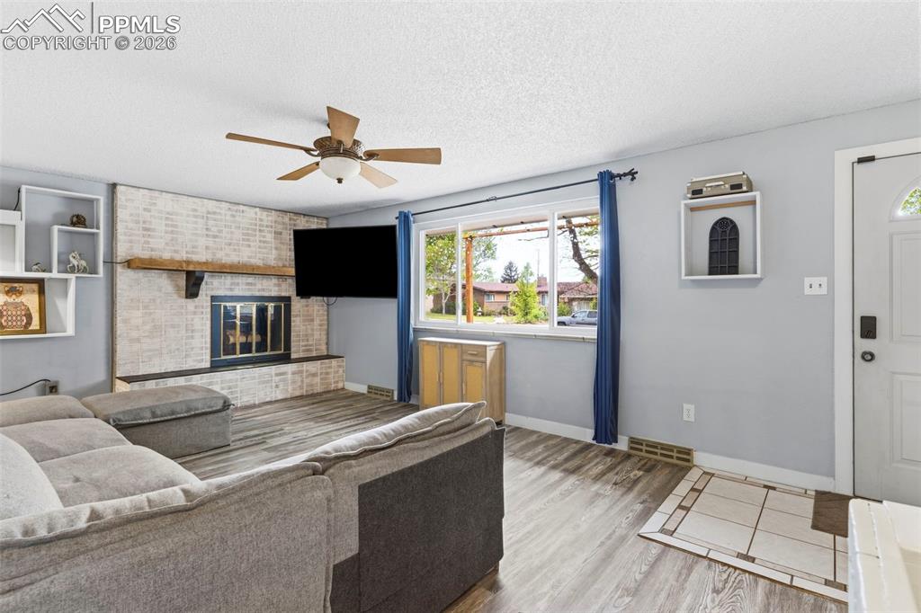 Image 6 of 37: Living area featuring wood-finish flooring, a brick-surround fireplace with