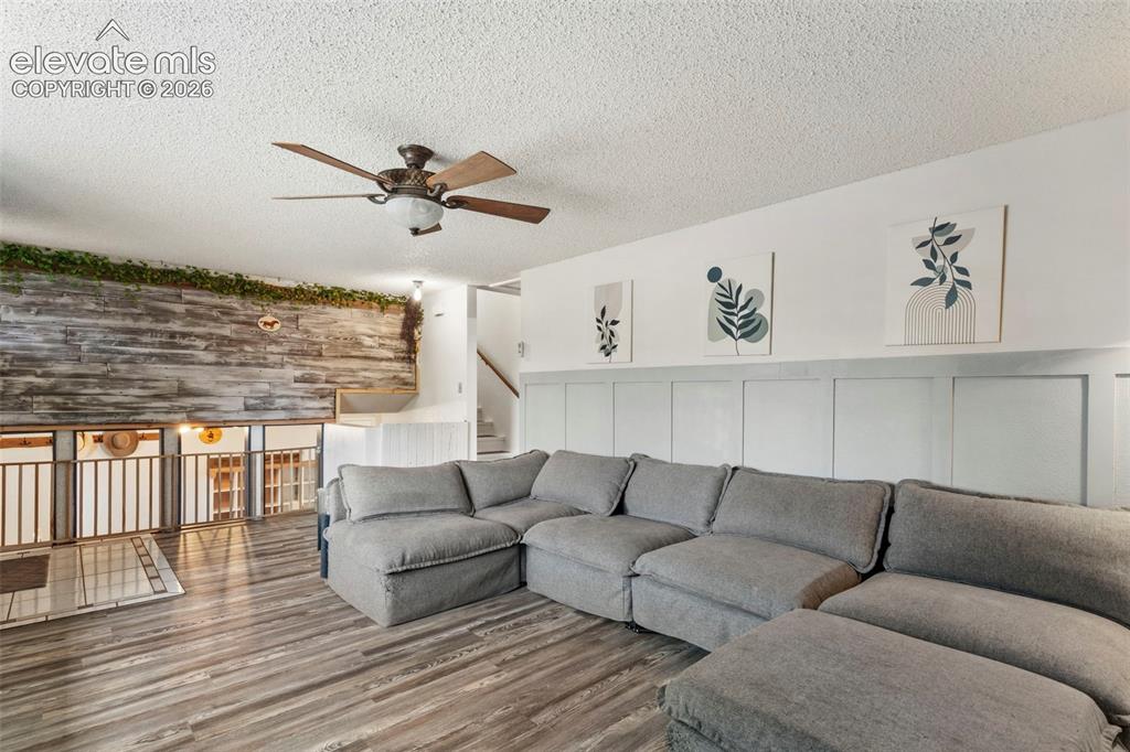 Image 6 of 37: Spacious living area featuring wood-finish flooring and a textured accent w