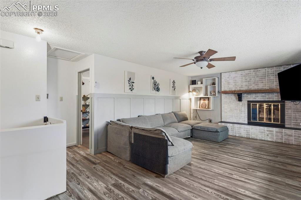 Image 7 of 37: Spacious living area featuring wood-finish flooring and a textured accent w