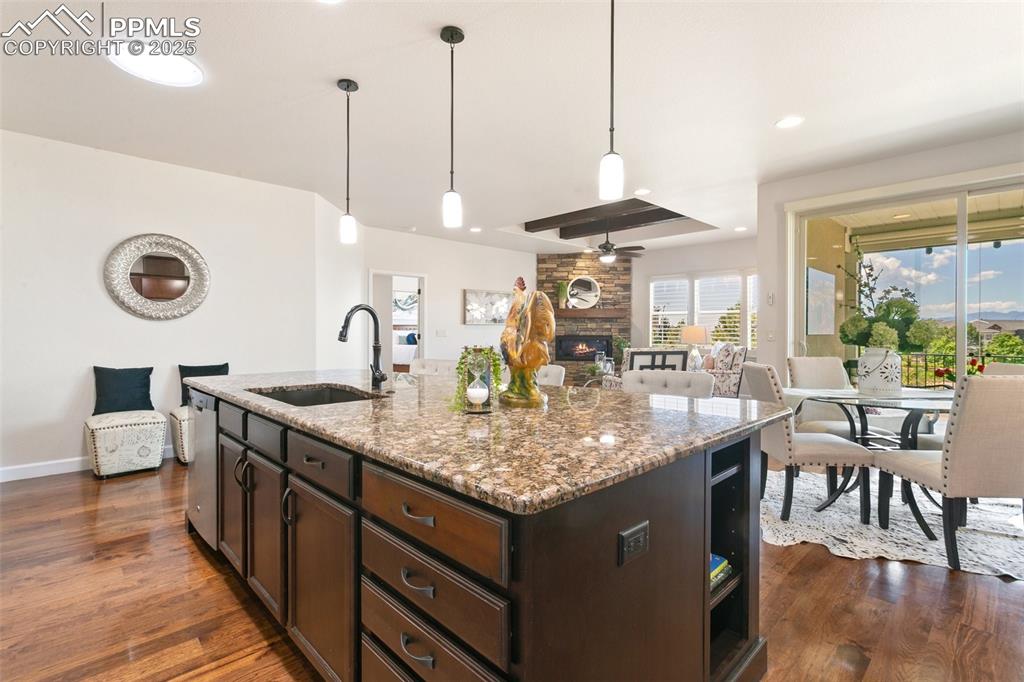 Image 8 of 50: Kitchen with a stone fireplace, dark wood-style flooring, ceiling fan, dark