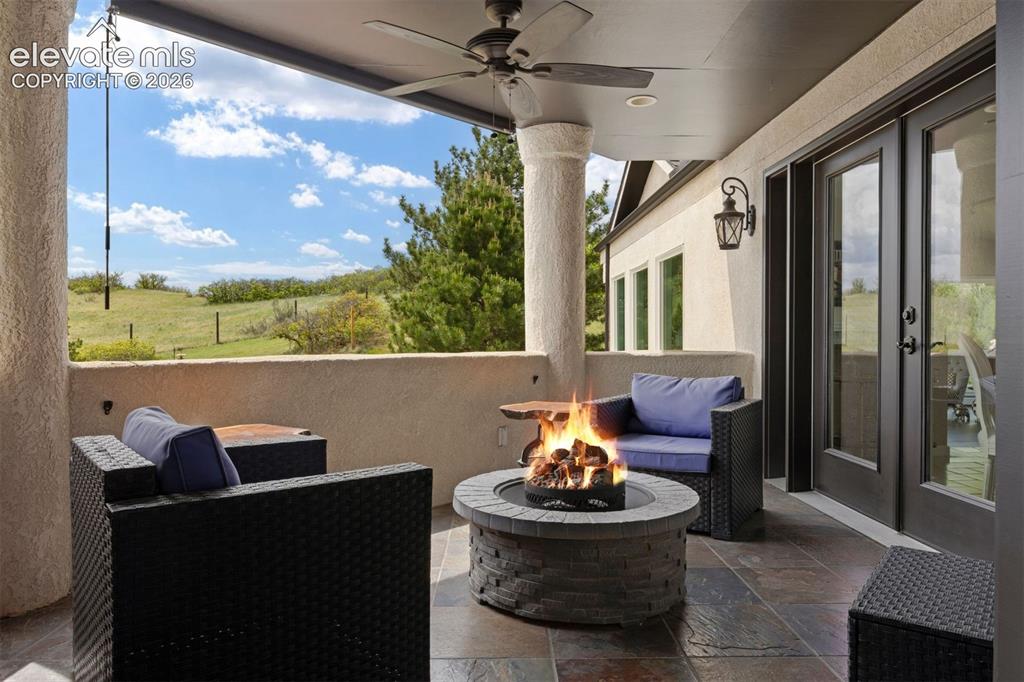 Image 28 of 38: Spacious patio with multiple outdoor seating areas and lush hillside landsc