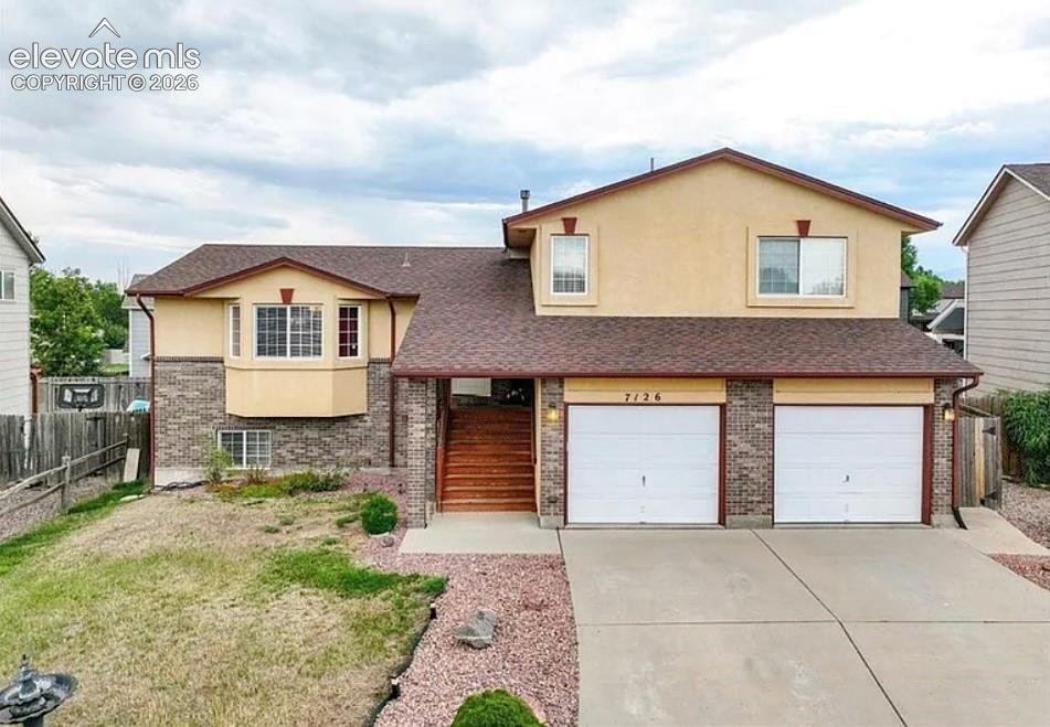 Caption: Two-story residence featuring a stucco and brick facade, a two-car garage, and a concrete driveway