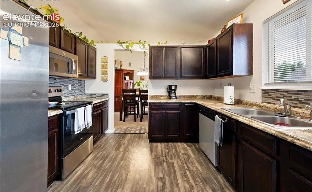 Image 4 of 20: Kitchen featuring dark wood cabinetry, stainless steel appliances, wood-fin
