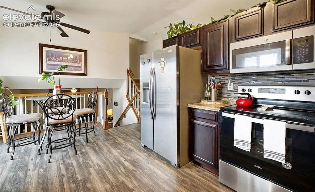 Image 5 of 20: Kitchen featuring wood-finish flooring, dark wood cabinetry, stainless stee