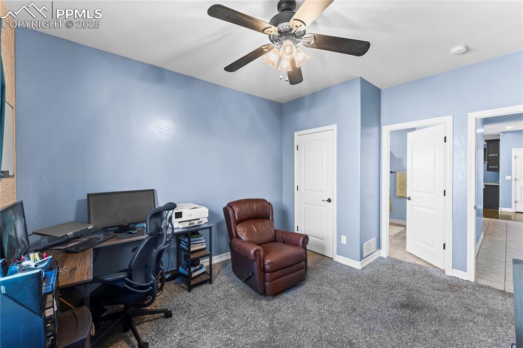 Image 11 of 48: Main Level Bedroom/Office featuring carpet flooring and a ceiling fan