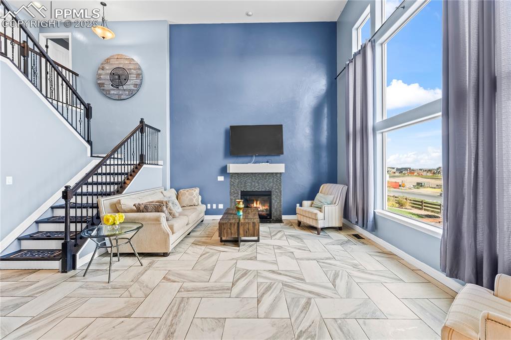 Image 14 of 48: Main Level Living room with stairway, a glass covered fireplace, and a towe