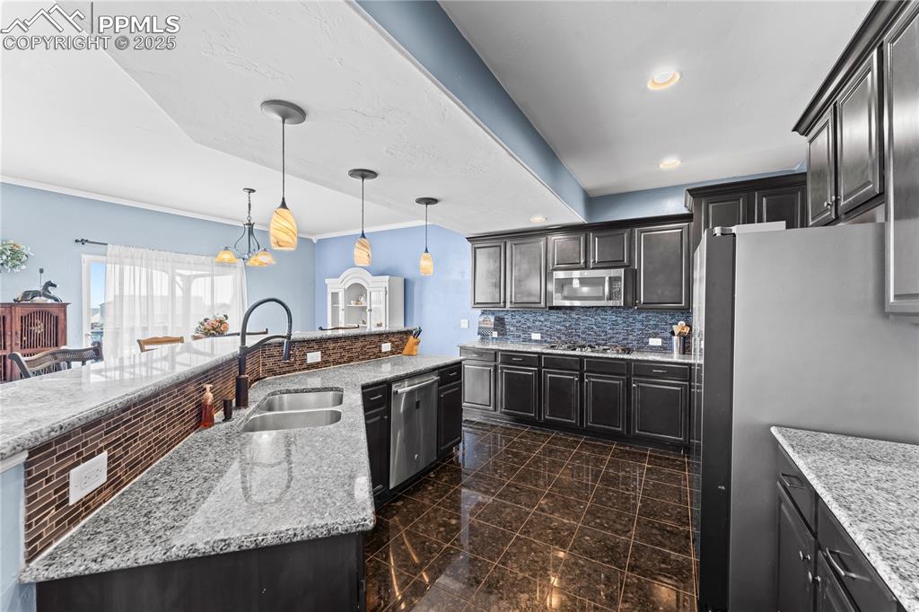 Image 16 of 48: Main Level Kitchen featuring decorative backsplash, light stone countertops