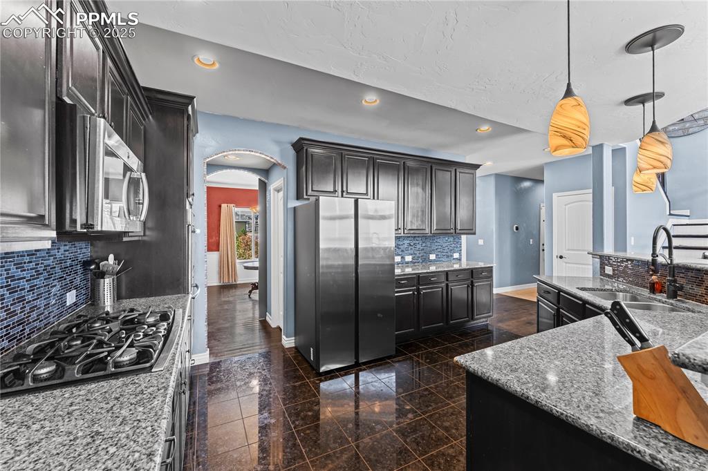 Image 17 of 48: Main level Kitchen featuring arched walkways, backsplash, granite floors, s