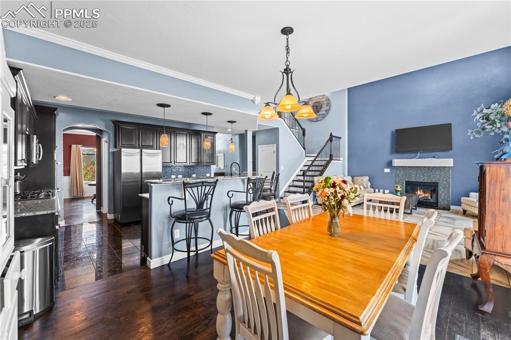 Image 18 of 48: Main Level Dining space with arched walkways, a tile fireplace, stairs, dar