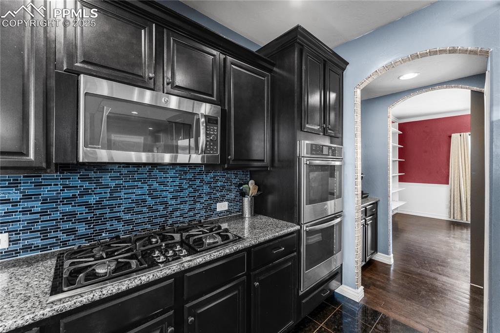 Image 19 of 48: Main Level Kitchen with dark cabinets, stainless steel appliances, dark sto