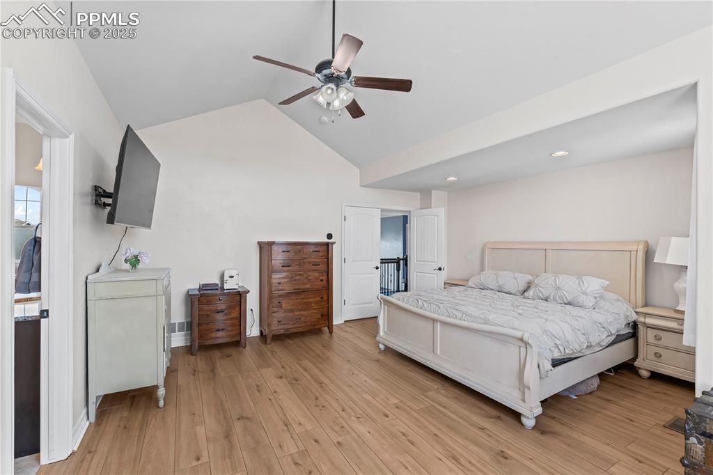 Image 21 of 48: Primary Bedroom featuring a ceiling fan, vaulted ceiling, and light wood fi