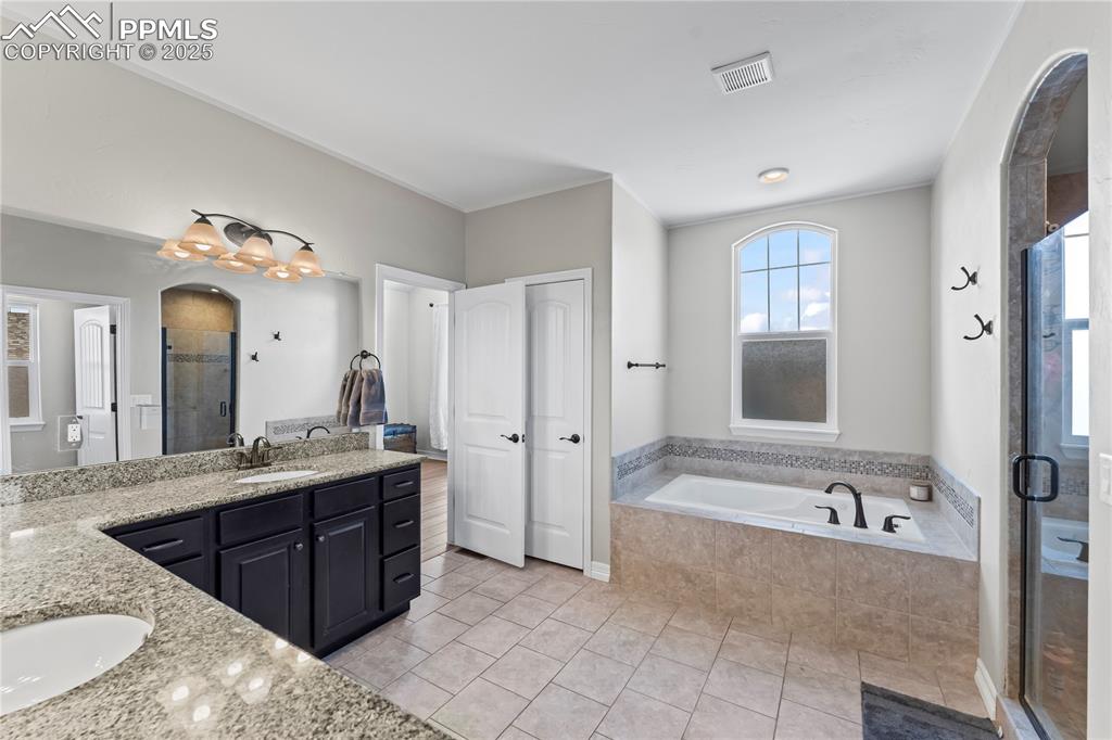 Image 23 of 48: Primary Bathroom with a shower stall, double vanity, light tile patterned f