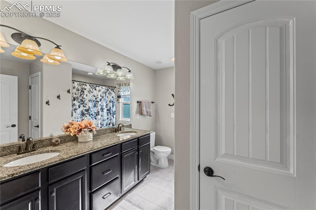 Image 30 of 48: Upstairs full bath featuring double vanity, light tile patterned floors, an