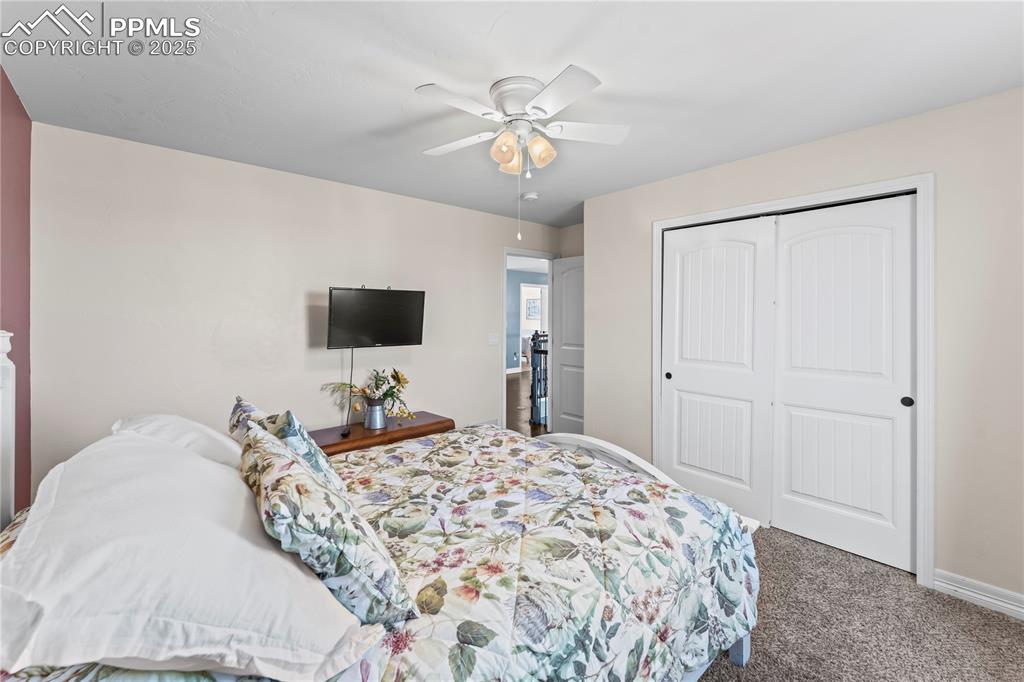 Image 33 of 48: Upstairs Bedroom with carpet, a closet, and a ceiling fan