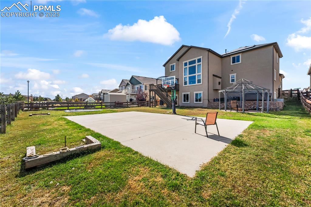 Image 44 of 48: View of sport court featuring a fenced backyard, basketball hoop, a patio, 
