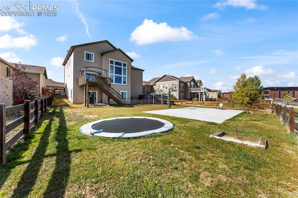 Image 45 of 48: Back of property featuring a trampoline, a patio area, a fenced backyard, s