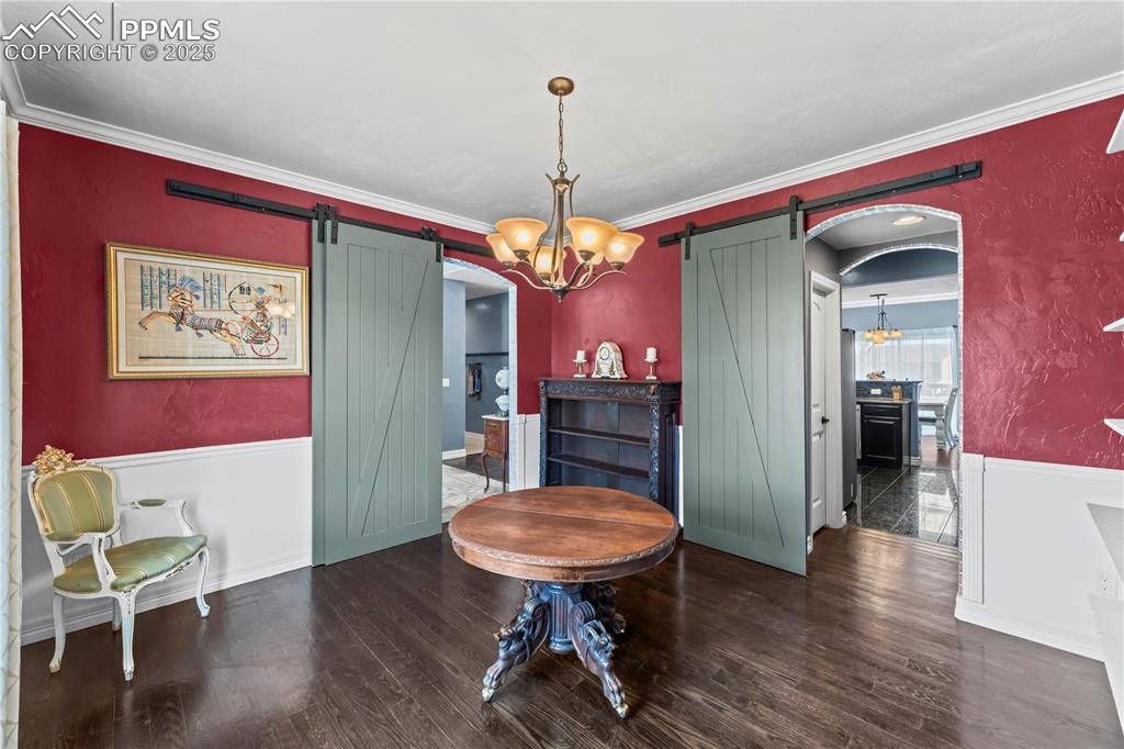 Image 8 of 48: Main Level formal dining room with a chandelier, wainscoting, a barn door, 
