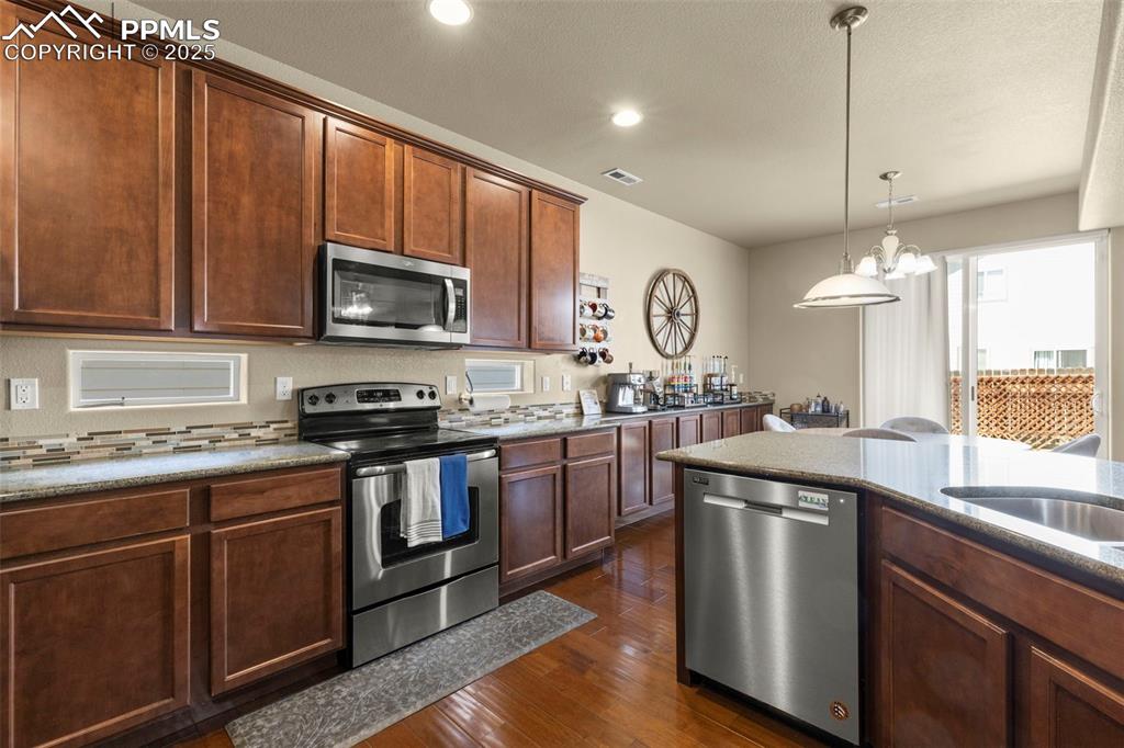 Image 10 of 27: Kitchen featuring stainless steel appliances, dark wood-style floors, a cha