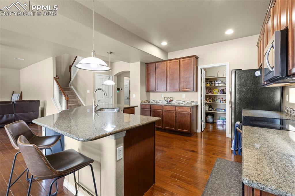Image 11 of 27: Kitchen with stainless steel microwave, arched walkways, dark wood-style fl