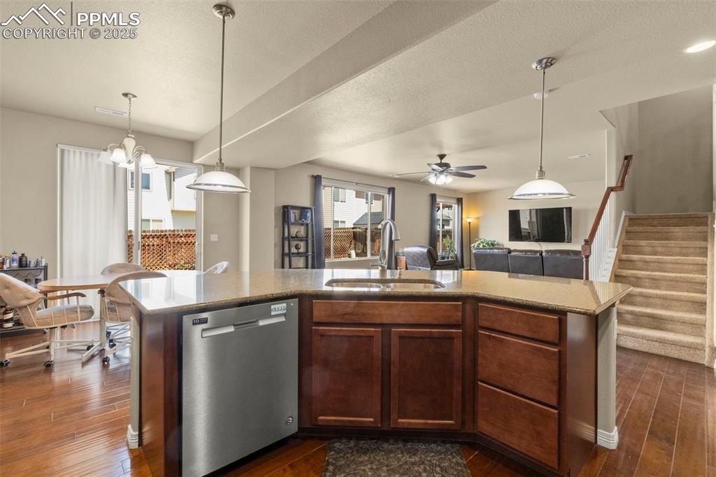 Image 12 of 27: Kitchen featuring stainless steel dishwasher, open floor plan, dark wood-ty