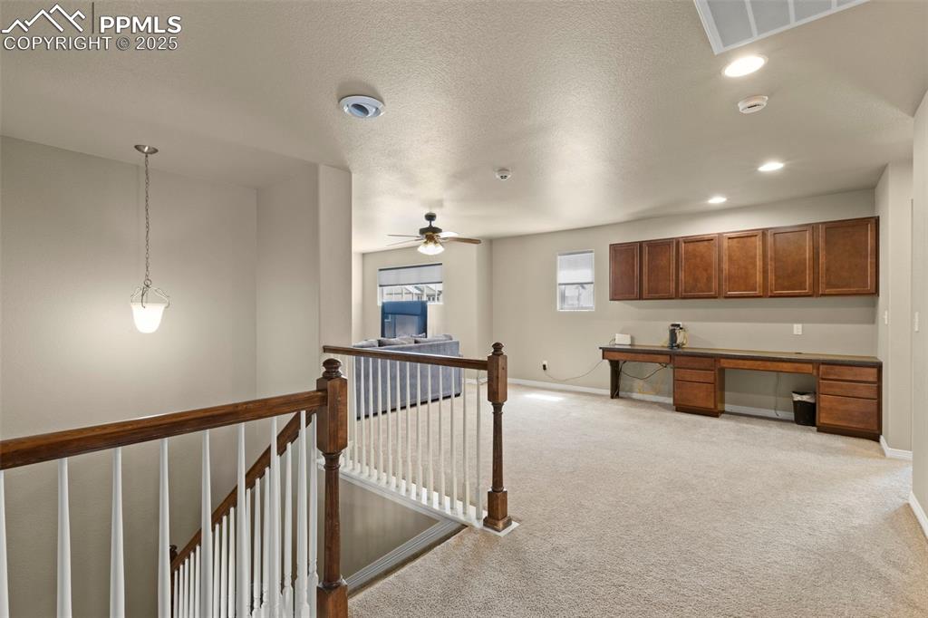 Image 20 of 27: Kitchen with built in desk, light colored carpet, recessed lighting, a ceil