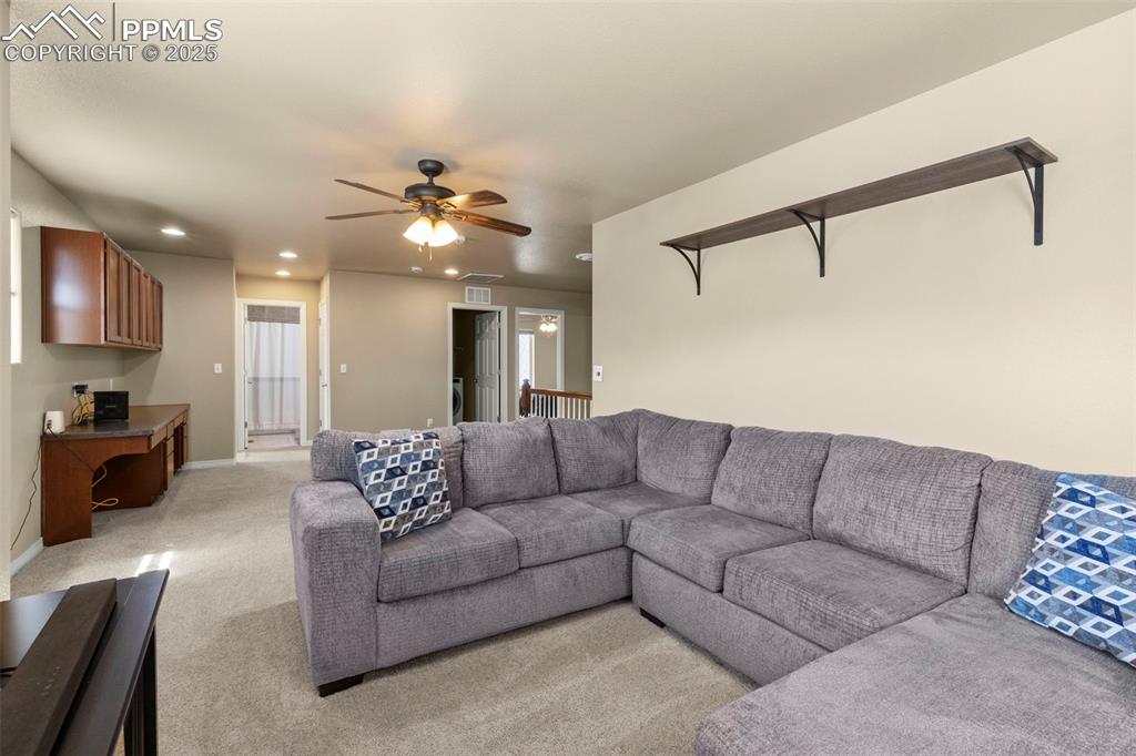 Image 23 of 27: Living area with a ceiling fan, recessed lighting, and light carpet