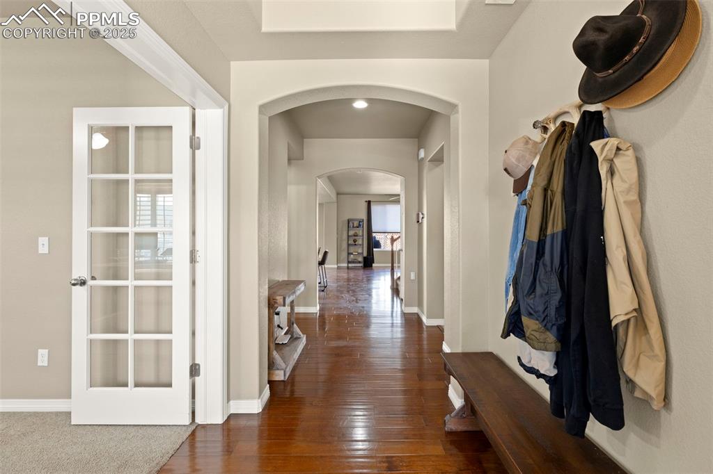 Image 6 of 27: Hallway with arched walkways and hardwood / wood-style floors