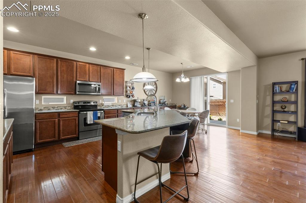 Image 9 of 27: Kitchen with stainless steel appliances, a breakfast bar area, dark wood fi