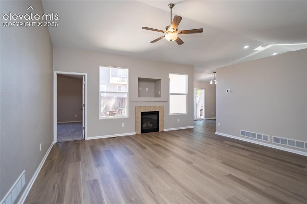 Image 11 of 39: Neutral LVP, vaulted ceilings, ceiling fan, lots of light, gas fireplace!