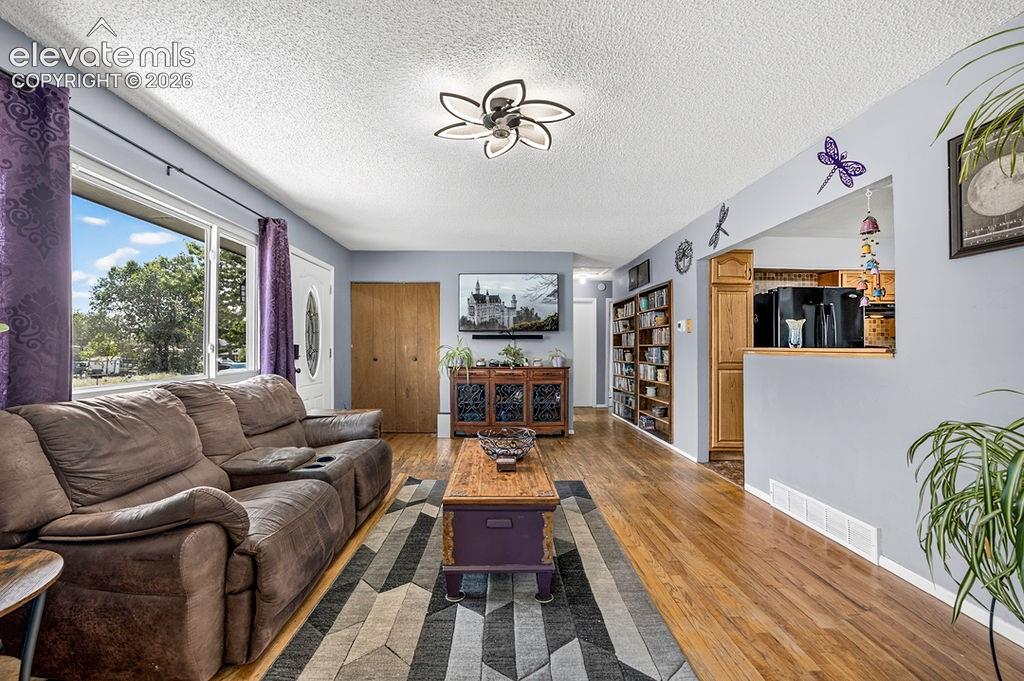 Image 10 of 44: Spacious living area featuring wood-finish flooring, a contemporary ceiling