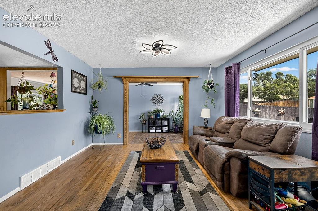 Image 11 of 44: Living area featuring wood-finish flooring, a pass-through window opening, 