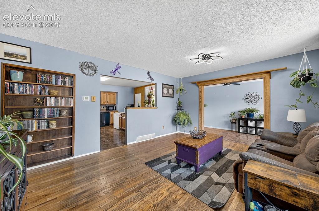 Image 12 of 44: Living area featuring wood-finish flooring, a built-in wooden bookcase, and