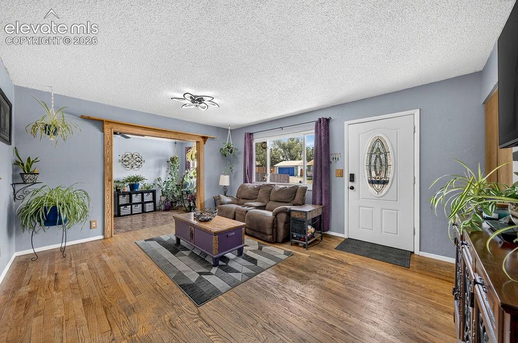 Image 13 of 44: Living space featuring wood-finish flooring, a white entry door with an ova