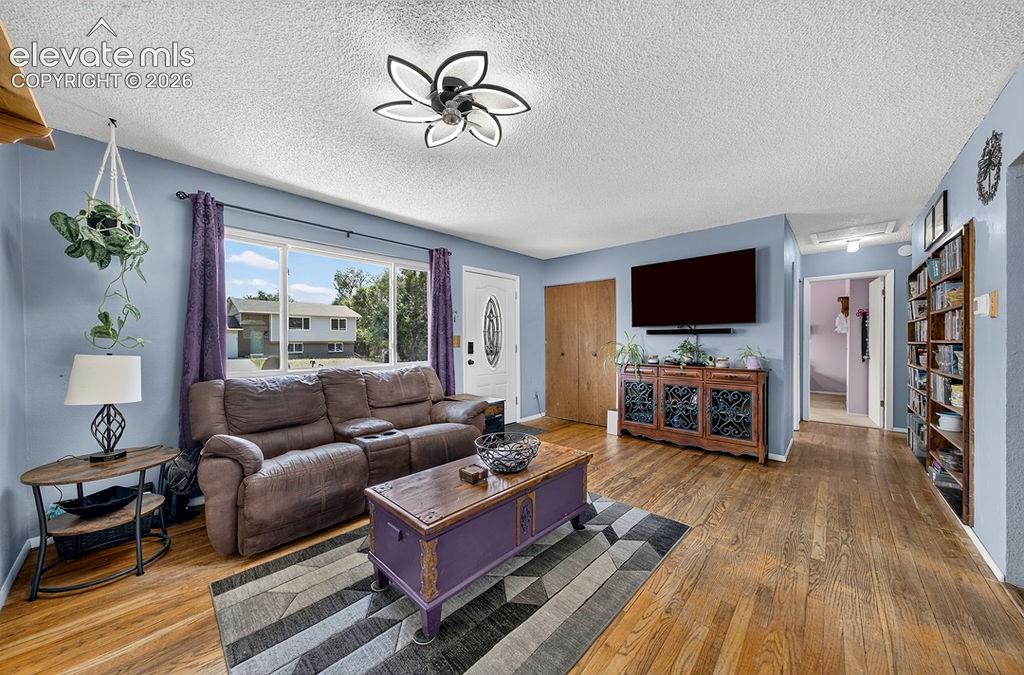 Image 14 of 44: Spacious living area featuring wood-finish flooring, a contemporary ceiling