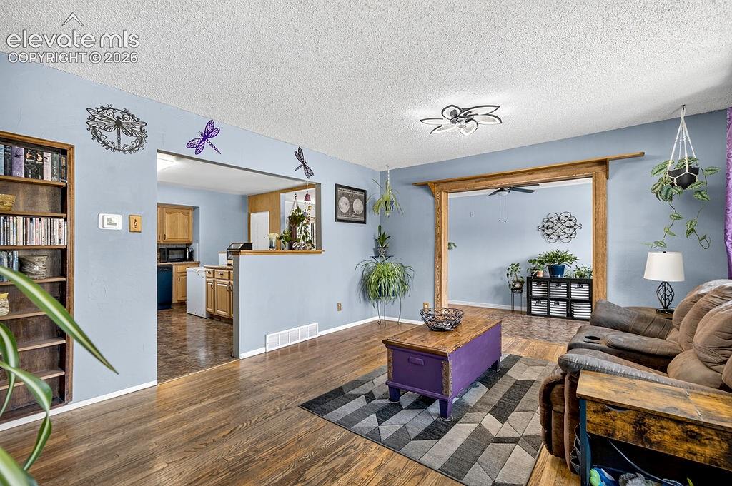 Image 16 of 44: Living area with wood-finish flooring, a wood-trimmed entryway, and an open