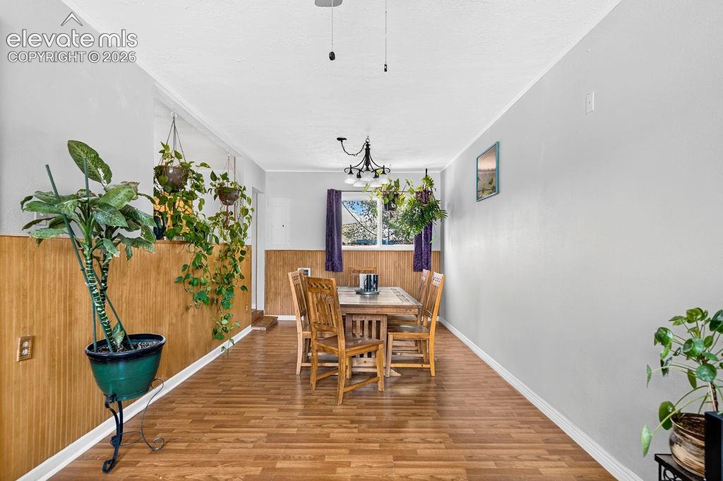 Image 18 of 44: Dining area featuring wood-finish flooring, two-tone walls with horizontal 